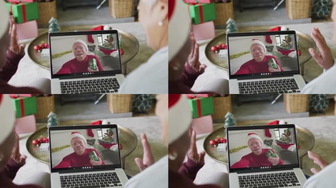 多元化的资深女性朋友使用笔记本电脑进行圣诞节视频通话，屏幕上有微笑的男人