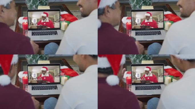 带有圣诞老人帽子的混血儿父子使用笔记本电脑进行圣诞视频通话屏幕上的圣诞老人