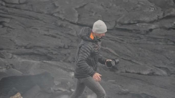 摄影师在冒烟的熔岩场中拿着相机
