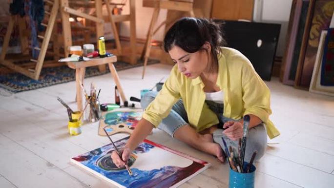 快乐的年轻女艺术家用丙烯酸涂料在画布上绘画
