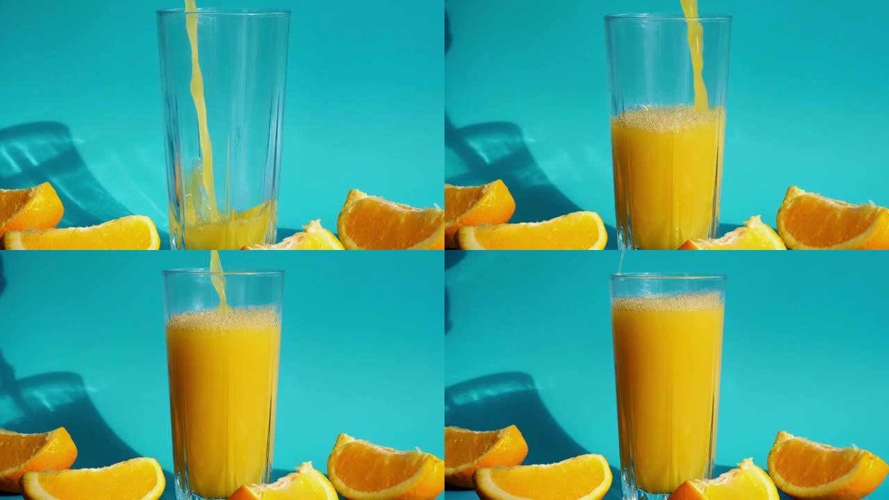 将橙汁从水罐中倒入一杯挤压橙汁，并在蓝色背景上切成薄片的水果。果汁，新鲜冷饮。夏天提神。水果切成两半