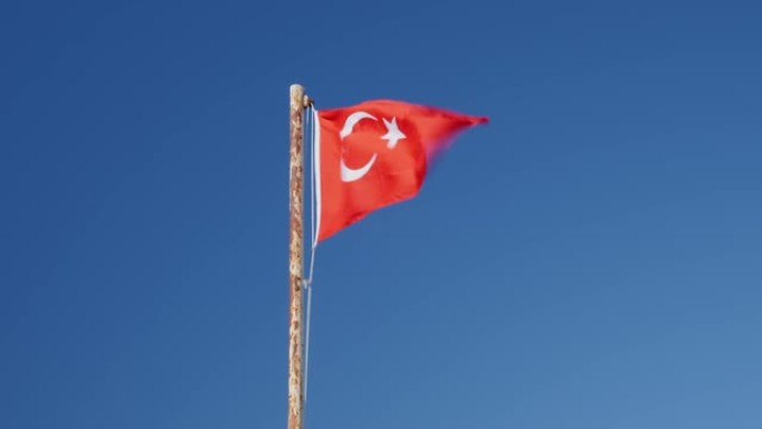 土耳其国旗在蓝天下迎风飘扬。旗杆上飘扬的红色土耳其国旗。土耳其国旗和标志