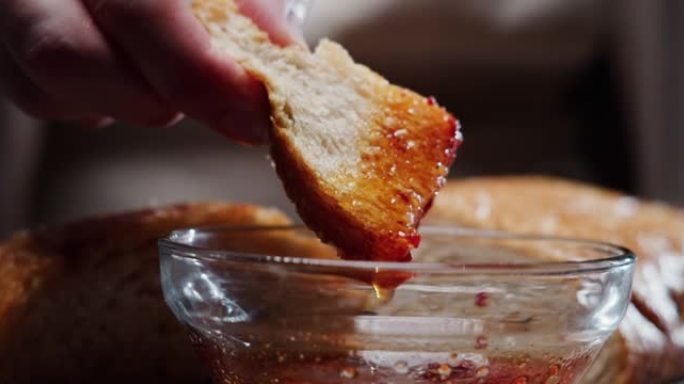 人手将一片意大利脆皮面包浸入番茄油中