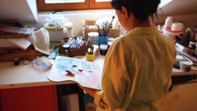 专注而有才华的女人，在她的艺术工作室在画布上绘画