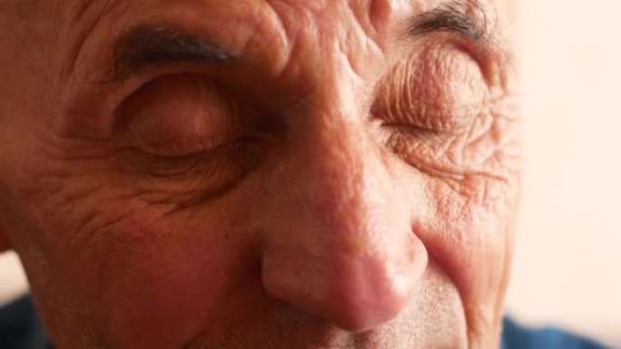 一位70岁以上白人老人的肖像。脸上有深深的皱纹的沉思老人。选择性聚焦。老人经常眨眼睛专心听