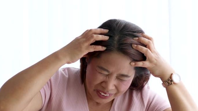 一名高级妇女用手握头头痛，痛苦不堪。老年人保健的概念。