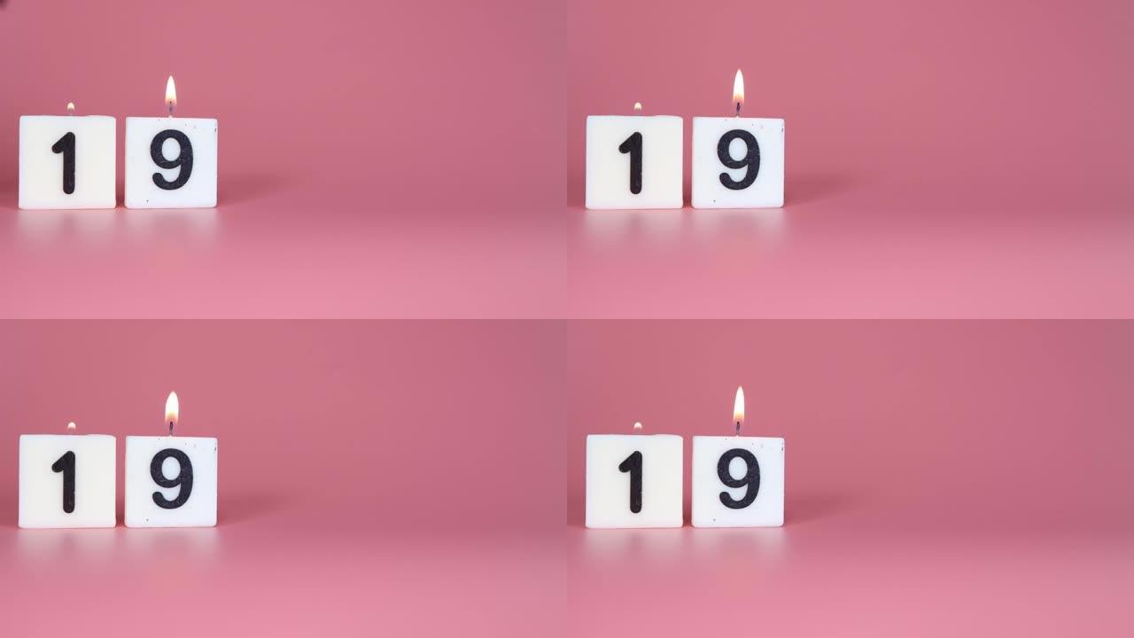一根方形蜡烛，上面写着19号被点燃并吹出粉红色的背景，庆祝生日或周年纪念日