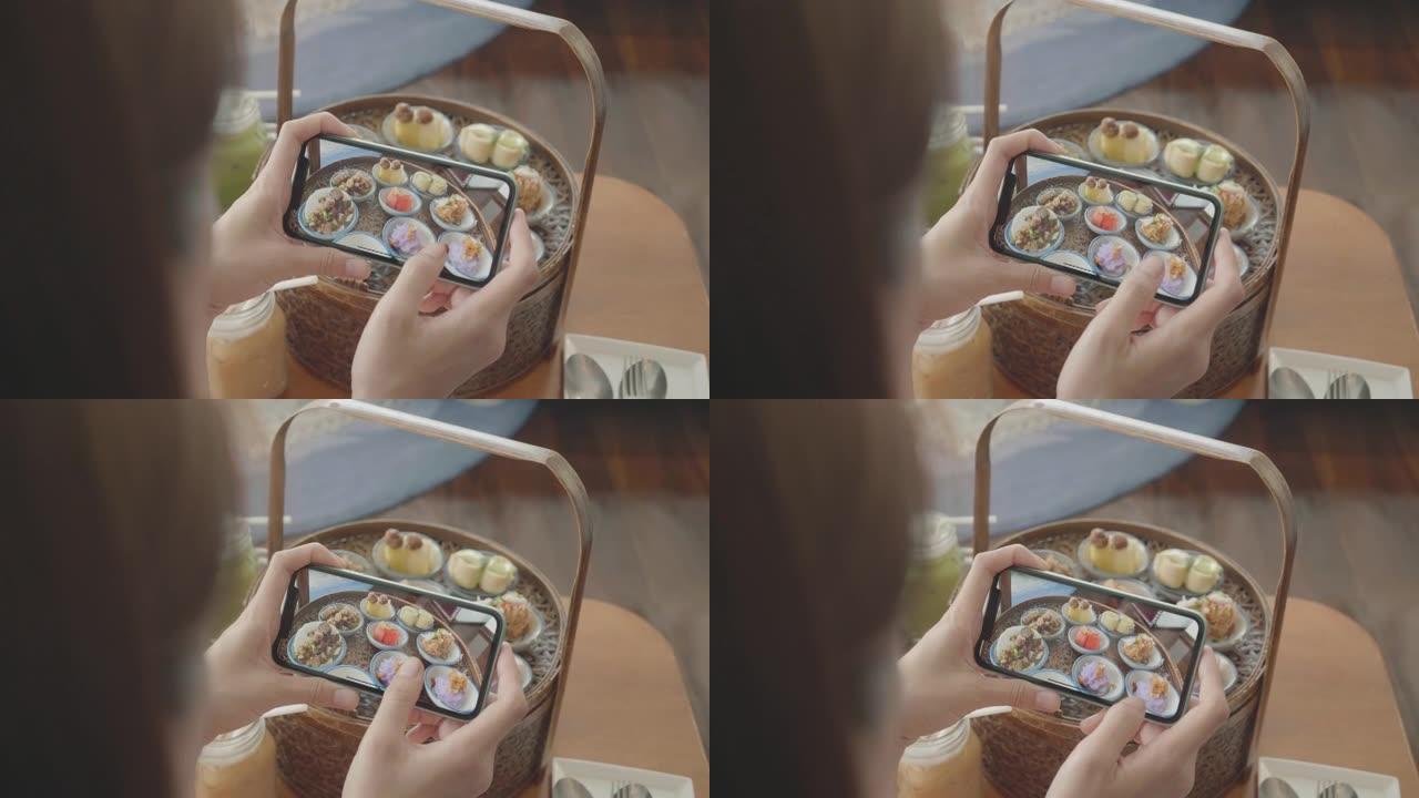 东南亚妇女在分享到社交媒体之前使用移动相机捕获泰国甜点