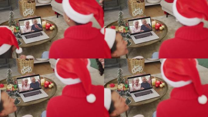 拥有圣诞老人帽子的多元化家庭使用笔记本电脑进行圣诞节视频通话，屏幕上有幸福的夫妇
