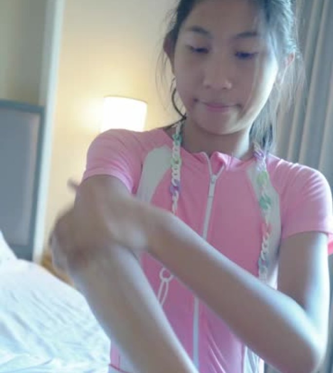 亚洲女孩在度假期间与家人在酒店或度假村游泳前在卧室涂抹防晒霜，生活方式理念。