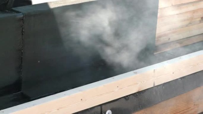在德国，屋顶工在屋顶上铺设带有火焰喷射器的焦油纸。你看到火焰和烟雾。
