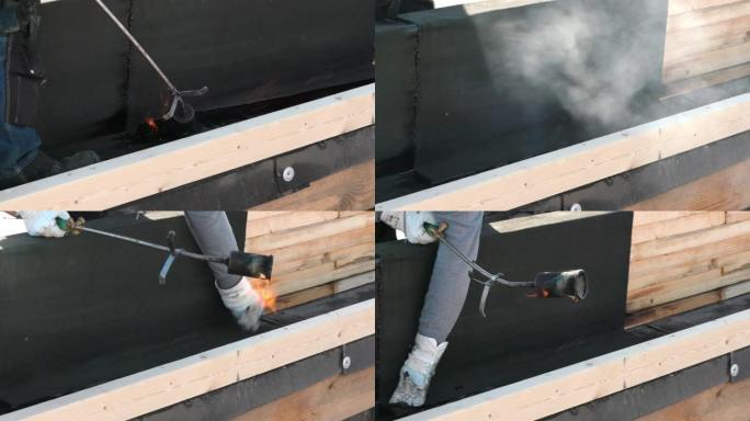 在德国，屋顶工在屋顶上铺设带有火焰喷射器的焦油纸。你看到火焰和烟雾。
