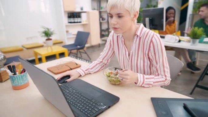 在笔记本电脑上工作时，现代女性企业家正在吃sald