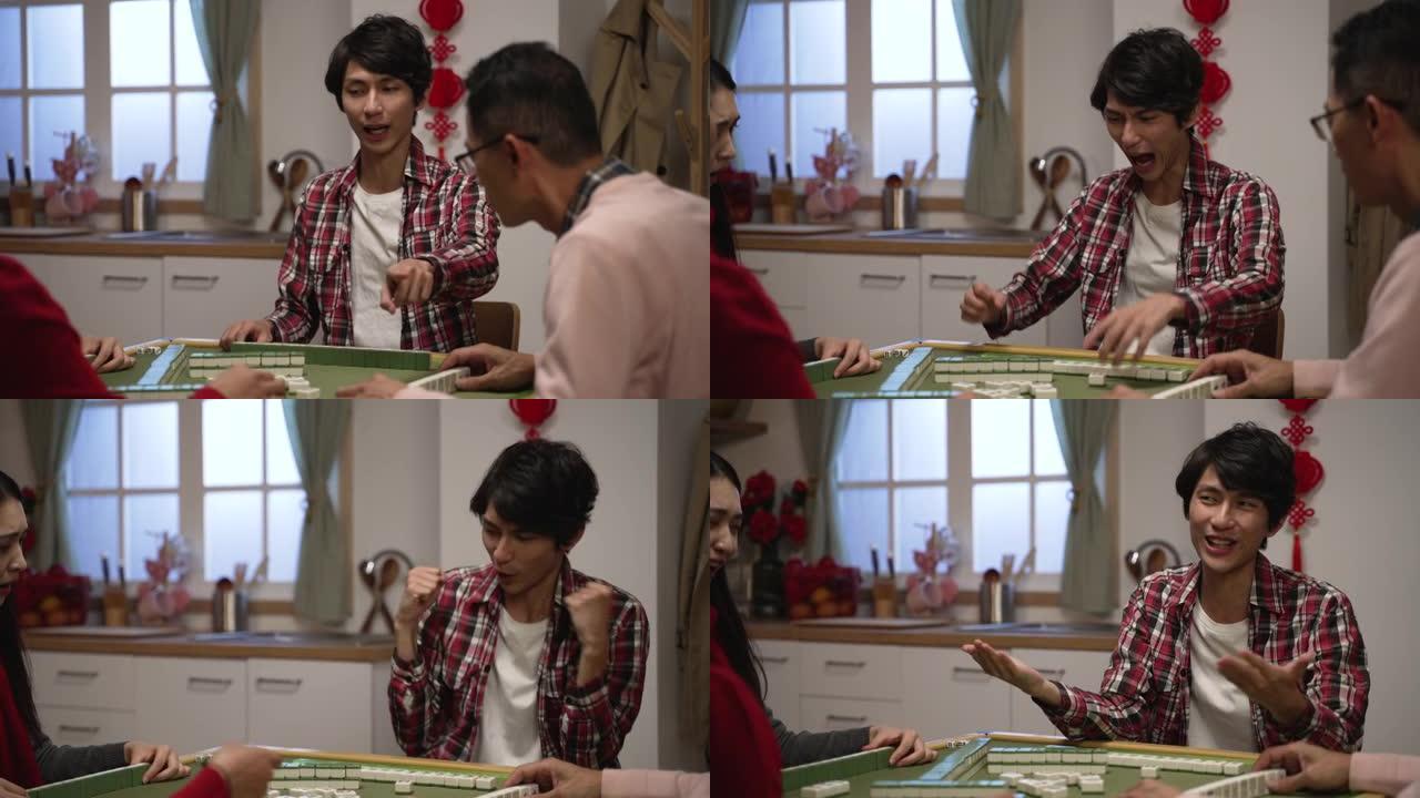 兴奋的亚洲儿子穿着红色的衣服，在春节期间在家里用手指指着欢呼着打麻将，用拳头打气，打着手势要钱