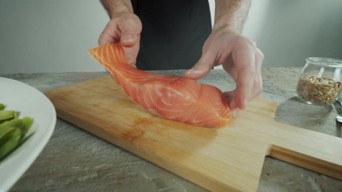 厨师把一条鱼放在木板上切片。特写