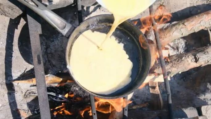 在大自然的旅游煎锅中，在篝火上煮煎蛋卷，慢动作