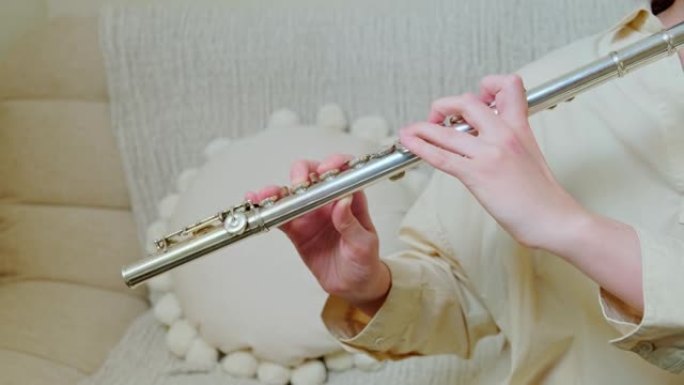 一个拿着笛子的女人手在客厅的沙发上在家演奏，特写