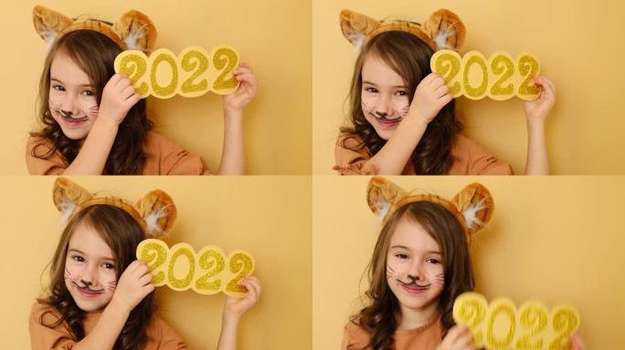 漂亮的女孩与耳朵和画脸的形象的老虎拿着辉煌的数字2022新年在她的手中。