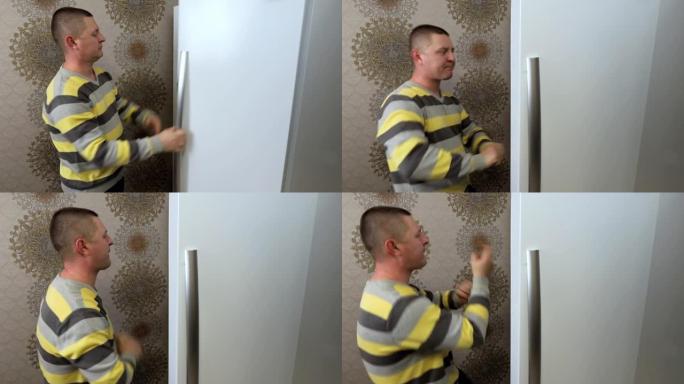 一个男人打开厨房的冰箱门，开始快乐地跳舞。