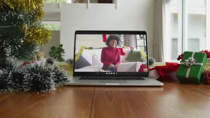 微笑的非洲裔美国妇女戴着圣诞老人的帽子在笔记本电脑上的圣诞节视频通话