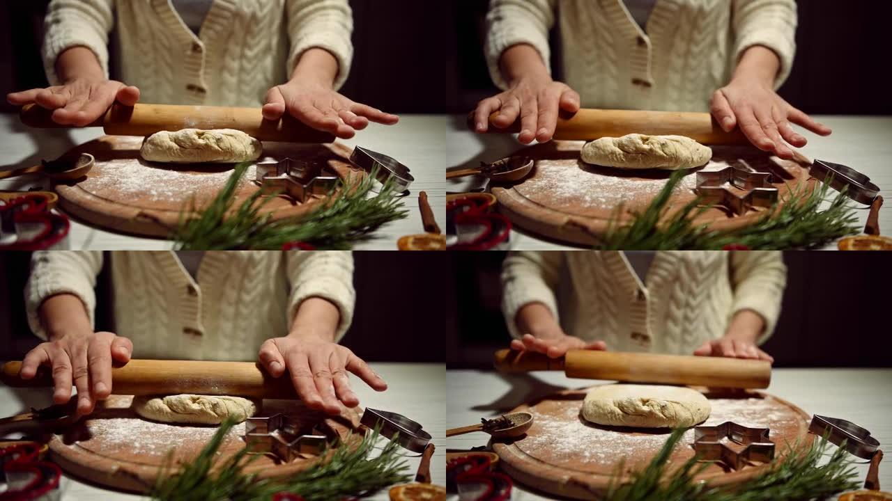 特写。女厨师用a面杖在木板上滚出面团，在厨房里准备圣诞节姜饼饼干。木桌上的松果、树枝和橙片。视频4K