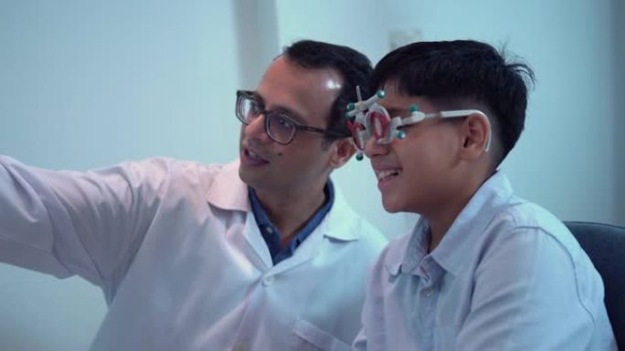 在眼镜店和验光师一起做视力检查的男孩，在光学店微笑的印度-泰国男孩选择眼镜