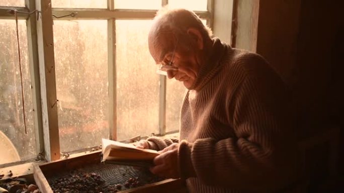 男人眼镜捡起灰尘中的旧书读在房子的窗户上