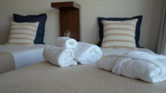 酒店带床和枕头的现代卧室房间的视频拍摄。还有白色毛巾和长袍给招待所游客。