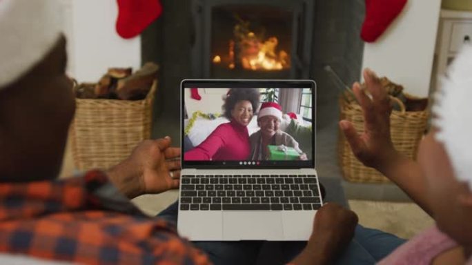 戴着圣诞老人帽子的非裔美国人夫妇使用笔记本电脑与家人在屏幕上进行圣诞节视频通话