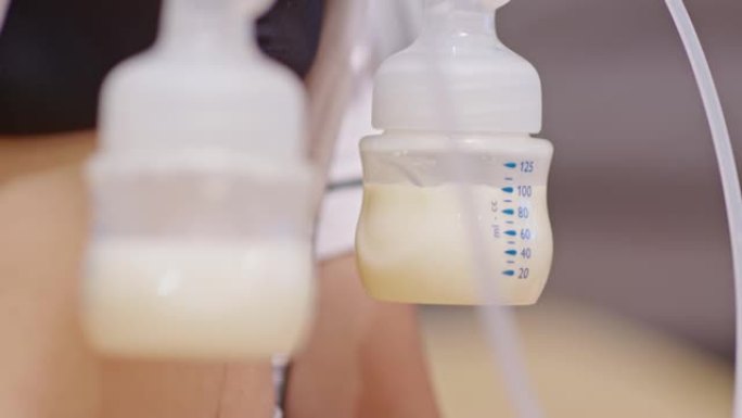 母亲为婴儿使用母乳泵。将吸奶器中的牛奶放入婴儿新生儿的奶瓶中。