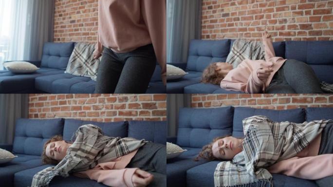 追踪白人年轻女子躺在沙发上并用毯子盖住的视频。用8k的红氦相机拍摄。
