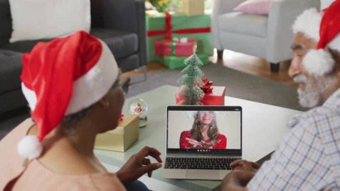 圣诞节时，与女性朋友在笔记本电脑上视频通话的快乐高级非洲裔美国夫妇