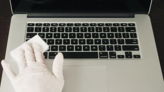 男人的手握住并捕捉消毒剂喷雾并对笔记本电脑，计算机进行消毒，以消毒人们的各种表面