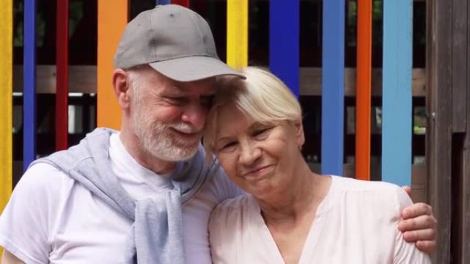 微笑的高级夫妇站在彩色墙壁背景下。无忧无虑的旅游家庭享受假期
