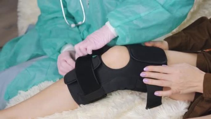 一名戴着医用手套的医生在病人受伤的腿上套上特殊的医用绷带。