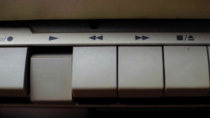 手指按下旧复古磁带播放器上的播放按钮，特写