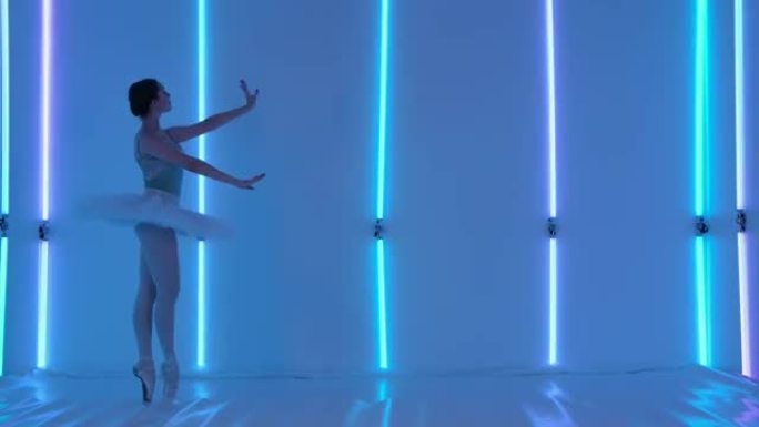 专业芭蕾舞演员在工作室里在彩色霓虹灯的背景下跳舞芭蕾舞。一个穿着舞台服装的女孩锻炼舞步，做出优雅的跳