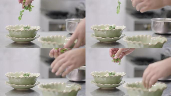 SLO MO: 男人的手将香菜叶放入椰奶汤碗中。