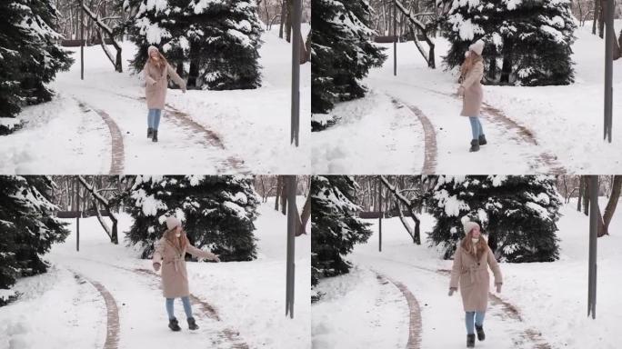 一个穿着米色外套的年轻美女在白雪覆盖的道路上奔跑和跳舞。