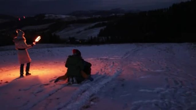 带着火把的母亲正在与雪橇孩子一起奔跑