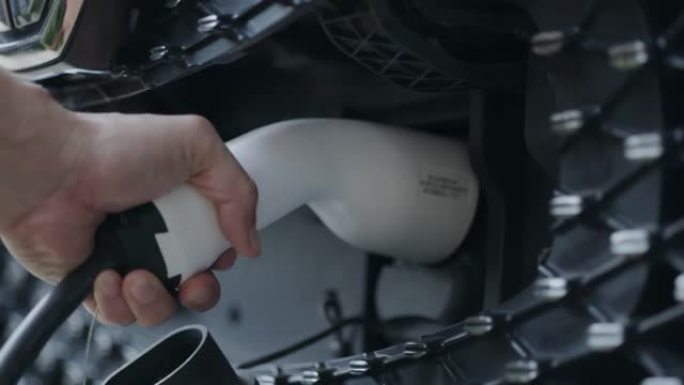 充电手为电动汽车提供动力的特写镜头。未来的汽车技术。节约能源保护环境