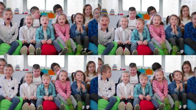 残疾儿童花时间与健康的孩子，男孩和女孩坐在豆袋椅上对着镜头微笑