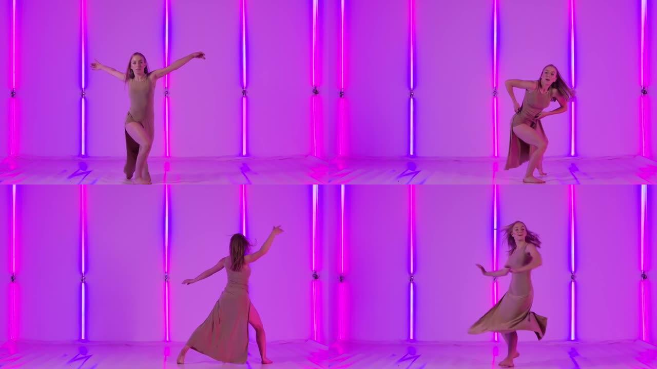 女性舞者表现出感性的蔑视，并在明亮的霓虹灯的背景下优雅地跳跃。年轻女子在黑暗的工作室里跳舞现代舞蹈。