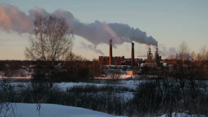 工厂管道在日落时冒烟。