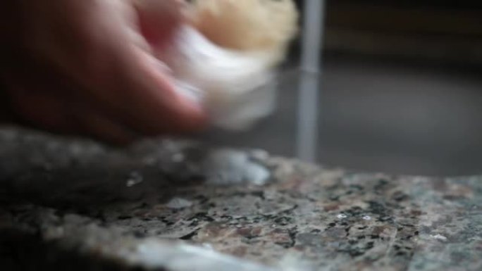 一名男子在巴西的厨房中用丝瓜作为海绵清洁盘子