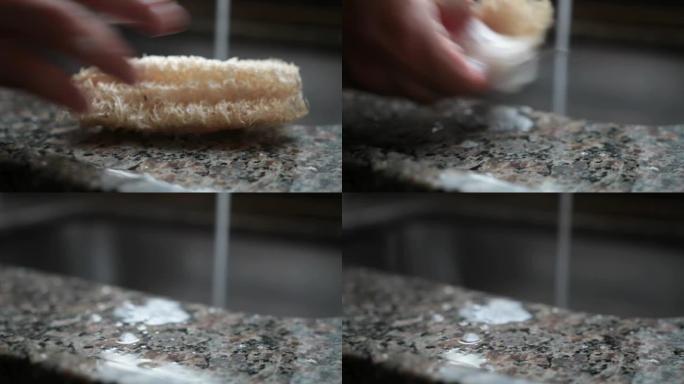 一名男子在巴西的厨房中用丝瓜作为海绵清洁盘子