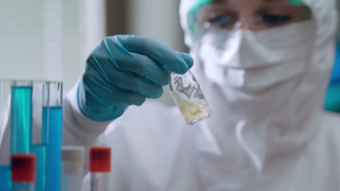 科学研究人员在实验室进行实验，以开发针对肺炎感染的潜在疫苗。保护性工作服的女性病毒学家手里拿着潜在的