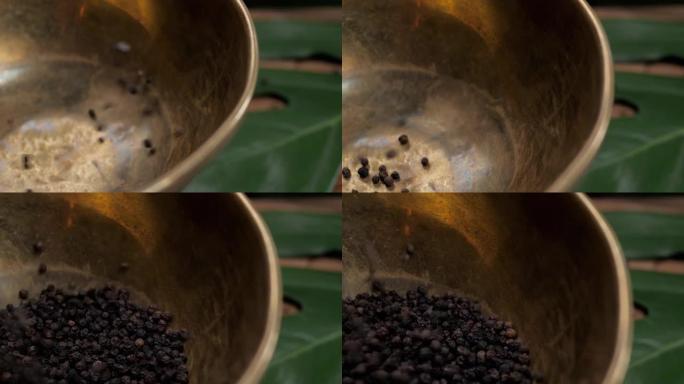 旧木桌上的整块和磨碎的黑胡椒倒在碗里。胡椒品种。磨碎的黑胡椒。木质背景上的黑胡椒玉米和黑胡椒粉。特写