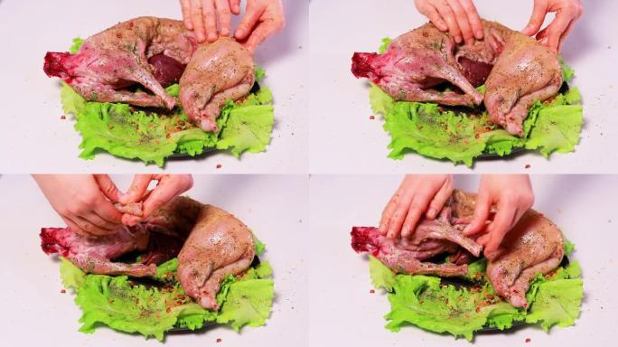 厨师将兔肉腌制-用调味料，盐和柠檬在白色背景的生菜叶上摩擦。烹饪兔肉