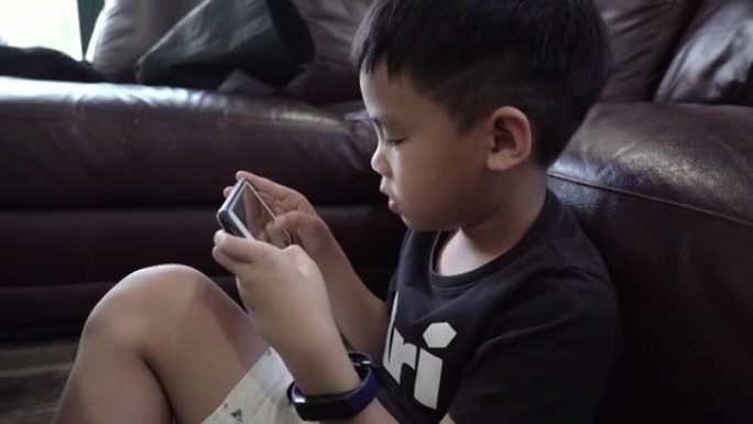 亚洲男孩玩智能手机游戏。